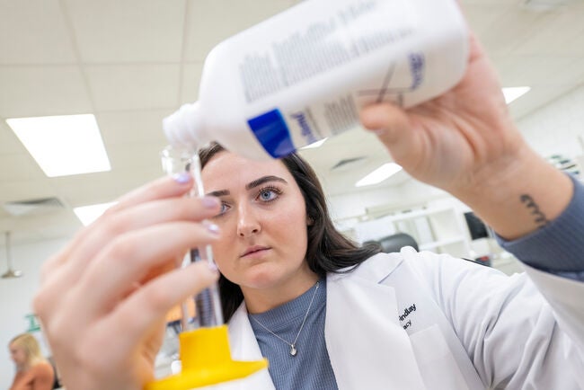 up close shot of student pouring liquid into test tube