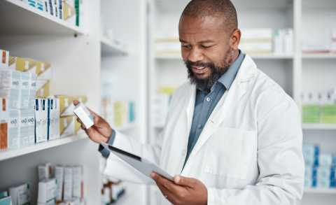Career pharmacist checking prescription with tablet